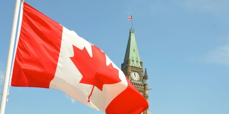 canadian-flag-waving-near-parliament-clock-tower-against-a-clear-blue-sky.jpg