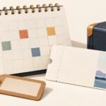Unmarked calendar beside a blank travel voucher, luggage tag and small travel case.