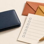 Closed navy wallet beside a blank bill checklist and two envelopes.