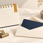 Unmarked renewal calendar beside a card in a cream envelope and a brass clip.